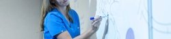 Nursing student draws on whiteboard.