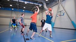 Students playing basketball inside gym.