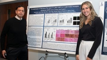 Faculty and student stand with their poster presentation.