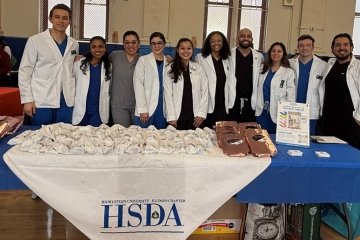 CDMI Students and Faculty stand near a table of information