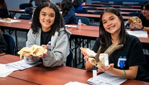 Two high school students holding up bones.