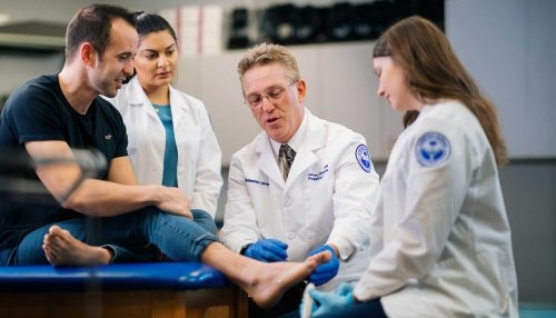 Professor examining foot while students observe.