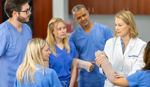 Doctor holding an arm with a cast in demonstration for students.