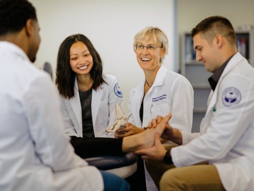 Podiatry faculty and students examine patient's foot.