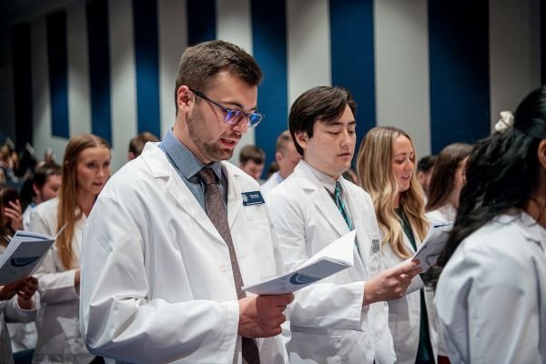 Students recite oath during white coat ceremony.